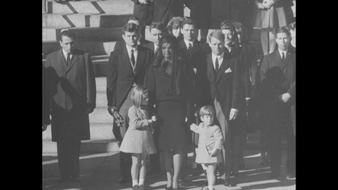1960s: Jackie Kennedy and family stand at funeral. John Kennedy salutes soldiers. Aerial view of presidential funeral parade in Washington DC.
