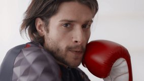 Boxing training. Close up portrait of young active man wearing boxing gloves punching to camera, exercising self-defence workout, slow motion