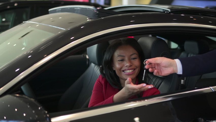 Female customer sitting inside car and receiving keys from salesperson during buying spbd. | Shutterstock HD Video #1072171331