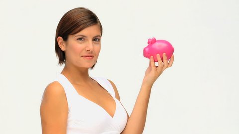 Brunette saving up money in a piggy bank isolated on a white background