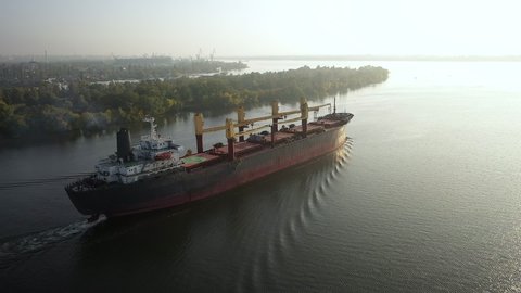 Slowmo aerial cargo bulker with bulk commodities sailing from seaport after loading coarse grain on ship to transfer seaborn trade goods. Logistics vessel on voyage. Merchant cargo with oats dispatch