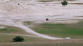 Two cars driving in spring off-road fields in Kitsevka, Ukraine, Kharkiv region landscape. Distant off-road driving scenery