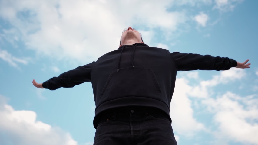 Happy Man in Black Hoodie Raises His Hands Up, Rejoicing in Success and Victory Against Background Beautiful Sky. Guy Experiences Sense Freedom and Well-being. Camera Rotates 360 Degrees. Slow Motion. | Shutterstock HD Video #1072179212