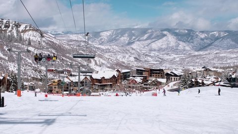 USA. Aspen. March 2021.Panoramic view on town in Colorado during winter season. People on skis and snowboards on the slopes of the ski resort. Ski elevator on snow mountain. 