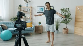 Mixed race man in sportswear is skipping on jumping rope and recording video for internet vlog at home. Active lifestyle and modern technology concept.