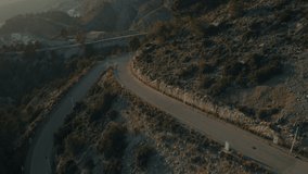 Cinematic and inspiring travel shot from drone of two friends ride on small vintage moped on beautiful winding mountain road. Epic motorcycle adventure on holiday