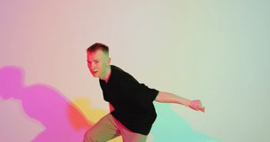 Dancing young guy cool moving in colourful studio light. Contemporary dance, hip hop freestyle. Advertising video