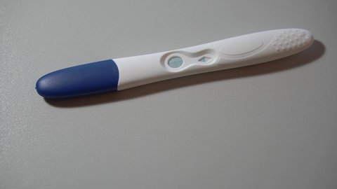 Pregnancy test is lying on a white background and revealing positive result in macro. Closeup view of medical equipment which is used to get known if woman is pregnant or not. Coming motherhood theme.