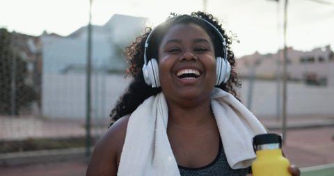 Curvy african woman smiling in camera while doing workout routine outdoor in the city - Plus size and sport concept