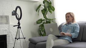 Beauty blogger woman filming at camera on tripod. Influencer lady live streaming review in home studio.