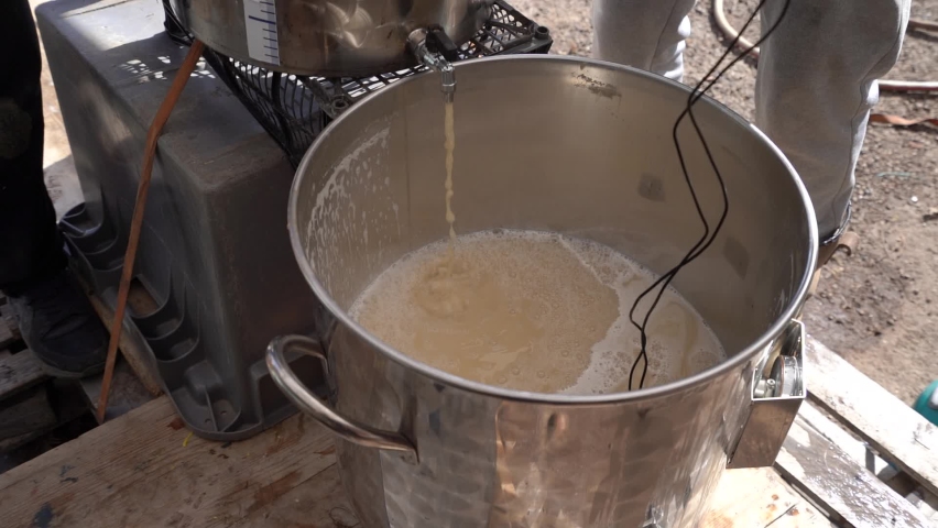Fresh brew flowing from a Hot liquor tank, into a Fermenter - Homebrewing of beer | Shutterstock HD Video #1072198733