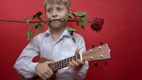 A child plays a ukulele and holds a rose in his mouth. Funny boy emotionally congratulates you on Valentine's Day. Happy birthday greeting video. Congratulations on Mother's Day. Women's Day
