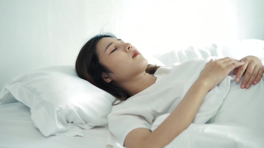 Asian young woman at the bed can't fall asleep, hand grabbed the pillow. Woman can not sleep because of loud noisefrom outside. 4K | Shutterstock HD Video #1072210679
