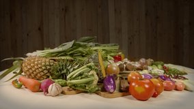 Preparing healthy vegetarian cooking materials. Fresh vegetables, 
spices and different types of mushrooms are placed on a white table with a wooden scene in the background. high quality 4K video
