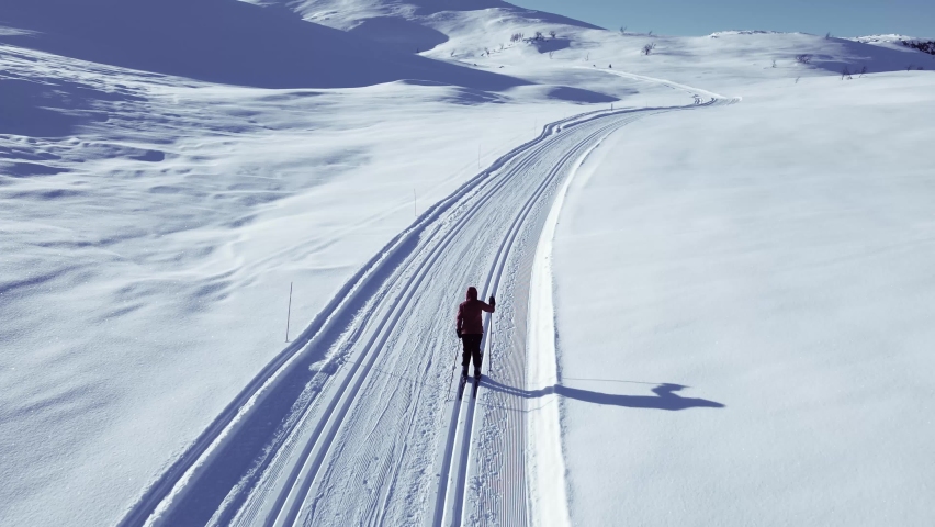 Person  cross country skiing on a slope through wild snowy mountain wilderness on a clear cold winters day.