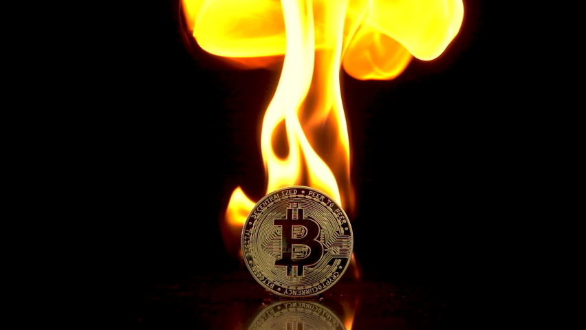 Bitcoin coin catches fire on an isolated black background. Slow motion 250fps.