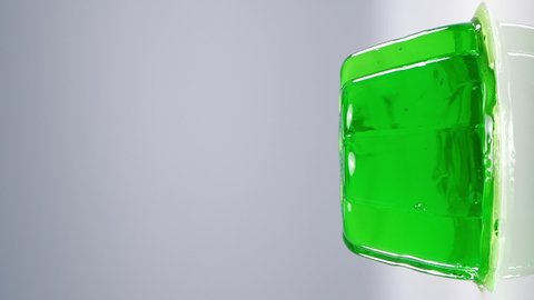 Wobbly single green jelly on white background. Vertical video.