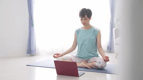 Middle-aged Asian woman taking online yoga. Mindfulness.