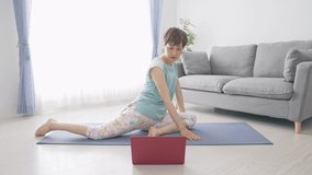 Middle-aged Asian woman taking online yoga.