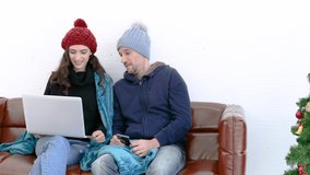 Happy couple greeting together by using laptop and wearing jacket in the house.