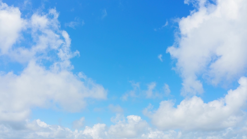 Bright white fluffy clouds fly across the blue sky on a sunny day. Summer beautiful cloudscape stock video. Clouds and sky without birds, copy space. Royalty-Free Stock Footage #1072231268