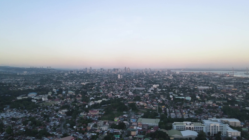 Aerial View of Metro Cebu City at Dusk. Shot Over Dense Urban Residential Areas. Zoom In and Wide Angle Drone Shot. 4K. Royalty-Free Stock Footage #1072231721