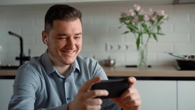 Happy man watching video smartphone online with wireless headphones at home indoors. Attractive Caucasian 30s portrait of businessman having rest from work using modern internet technologies concept - Powered by Shutterstock - Get 15% off with code: PIKWIZARD15