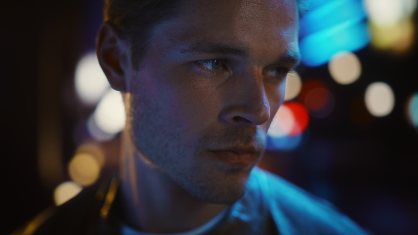 Portrait of Handsome Serious Man Standing, Turning and Looking at Camera with Night City with Bokeh Neon Street Lights. Focused Confident Intense Young Man. Close-up Shot with Cinematic Flares | Shutterstock HD Video #1072234739