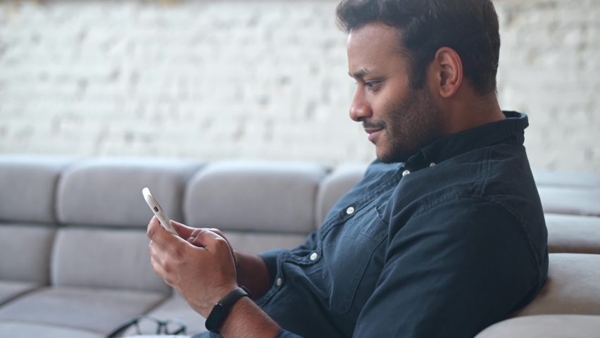 Positive indian guy using smartphone for online communication, smiling mixed-race guy browsing, scrolling news feed, messaging in social media,hindu man holds phone and enjoying new mobile application Royalty-Free Stock Footage #1072237991