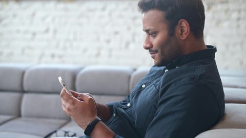 Positive indian guy using smartphone for online communication, smiling mixed-race guy browsing, scrolling news feed, messaging in social media,hindu man holds phone and enjoying new mobile application