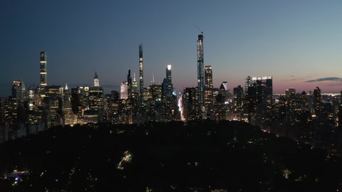 Moving Time Lapse Hyper Lapse over New York City Central Park at Night Towards Skyline of Manhattan Skyscraper with glowing City lights, Aerial Hyperlapse