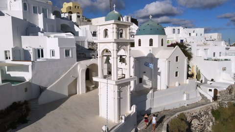 Aerial Tilt Down Shot Of Famous Anastasi Orthodox Church In City, Drone Ascending Over Whitewashed Structures On Sunny Day - Santorini, Greece