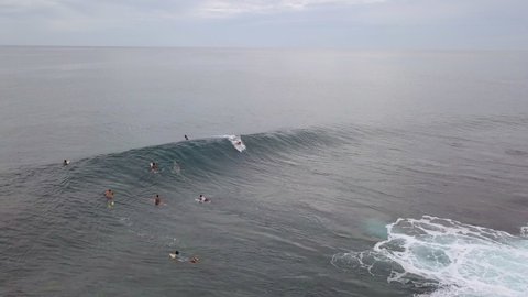 Aerial Shot Of People Surfing In Sea During Sunset, Drone Flying Backward Over Ocean - Siargao, Philippines