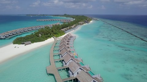 Aerial Shot Of Luxurious Water Bungalows On Turquoise Sea, Drone Flying Forward Over Resort Against Sky On Sunny Day - Kuramathi, Maldives