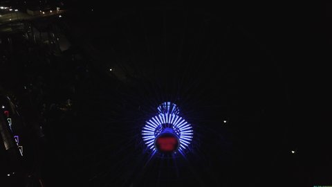 Aerial Lockdown Shot Of Illuminated Ferris Wheel At Pier In City Drone Flying Over Santa Monica Pier At Night