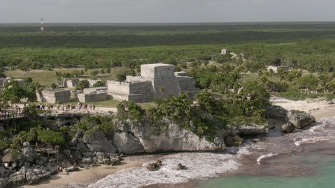 Aerial Panning Shot Of Tourists Exploring Famous Tulum Ruins Against Sky, Drone Flying Over People At Historic Landmark On Sunny Day
