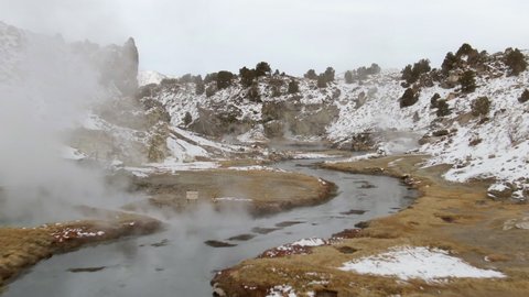 Aerial Shot Of Creek Emitting Steam Amidst Snow During Winter, Drone Flying Forward Over Hot Creek Geological Site Against Sky - Mammoth Lakes, California