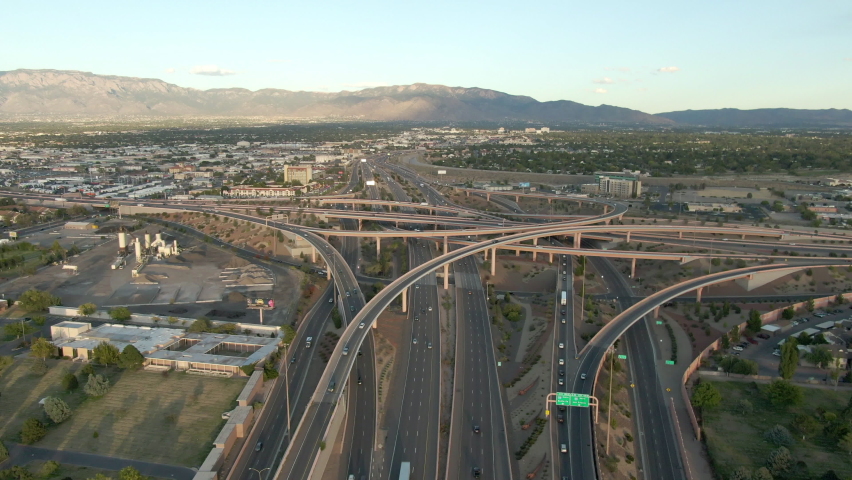 Aerial Tilt Down Shot Of Vehicles On Bridges In City Against Mountains, Drone Flying Forward Over Cars In City Against Sky At Sunset - Albuquerque, New Mexico