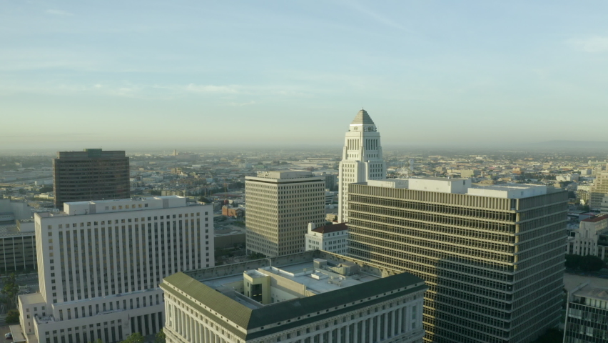 Aerial Moving Forward And Over La City Hall And Surrounding Government Buildings Under A Bright Sky With The City Suburbs Stretching Into The Distant Horizon - Los Angeles, California