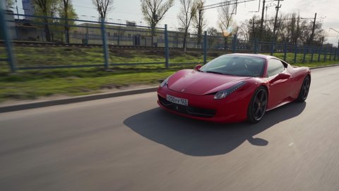 ROSTOV-ON-DON, RUSSIA - APRIL 27, 2021: crane moving rolling shot of a red Ferrari 458 Italia Coupe sports car driving in a city at day. Concept of business, traveling, luxury, lifestyle