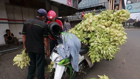 Ketupat or rice dumpling sellers on motorbikes, rice packets made of coconut leaves, around Pasar Wage, Purwokerto, Central Java, Indonesia. May 12, 2021