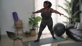 Young African woman doing pilates virtual fitness class with laptop at home - Sport wellness people lifestyle concept