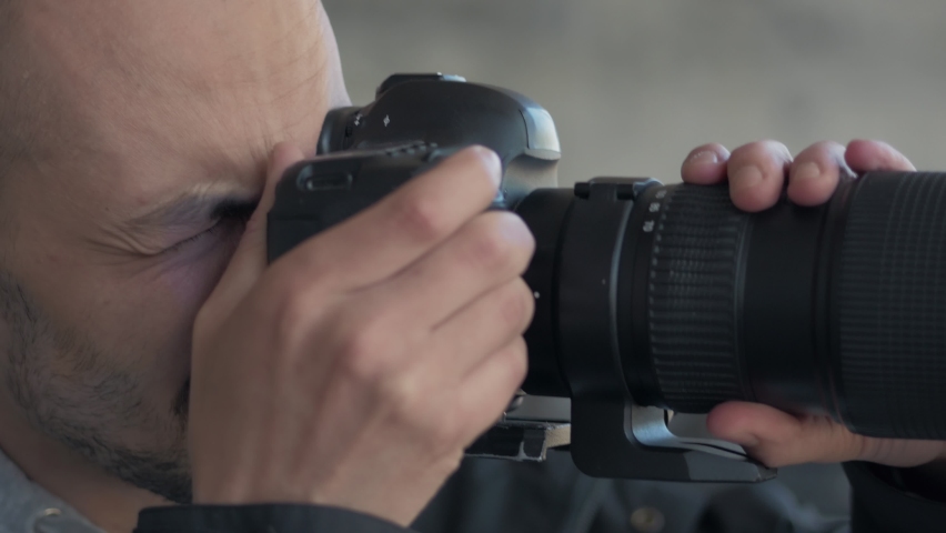 A man takes photos using a SLR camera with a large lens.