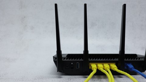 Wireless WIFI Router With Blue Patch Cord In WAN Connector And Yellow Patch Cords In LAN Connectors On Office Table Background. Panning Dolly Slider Shot.