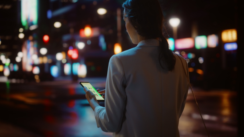Beautiful Woman Online Shopping on Smartphone while Walking Through Night City Street Full of Neon Light. Female Using Mobile Phone, e-Shop, Internet Clothing Store. Following Tracking Medium Shot | Shutterstock HD Video #1072294118