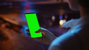 Woman using Chroma Key Smartphone while Standing, Gesturing, Swiping, Scrolling. Night City Street Full of Neon Light. Female Using Green Screen Mobile Phone. Over the Shoulder Close-up Shot - Powered by Shutterstock - Get 15% off with code: PIKWIZARD15