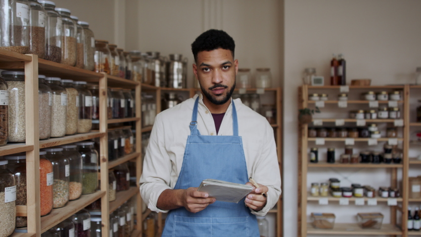 Male owner of zero waste shop, looking at camera.