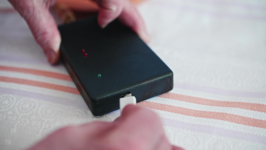 Close up of woman hands plugging USB cabel to socket of powerbank. Piece of alternative medecine.