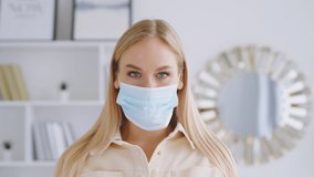 Young attractive girl taking off the medical blue mask. Beautiful smiling woman without medical mask looking at the camera