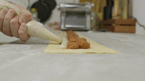 Chef adds mushroom sauce onto lasagna dough. Slow motion.